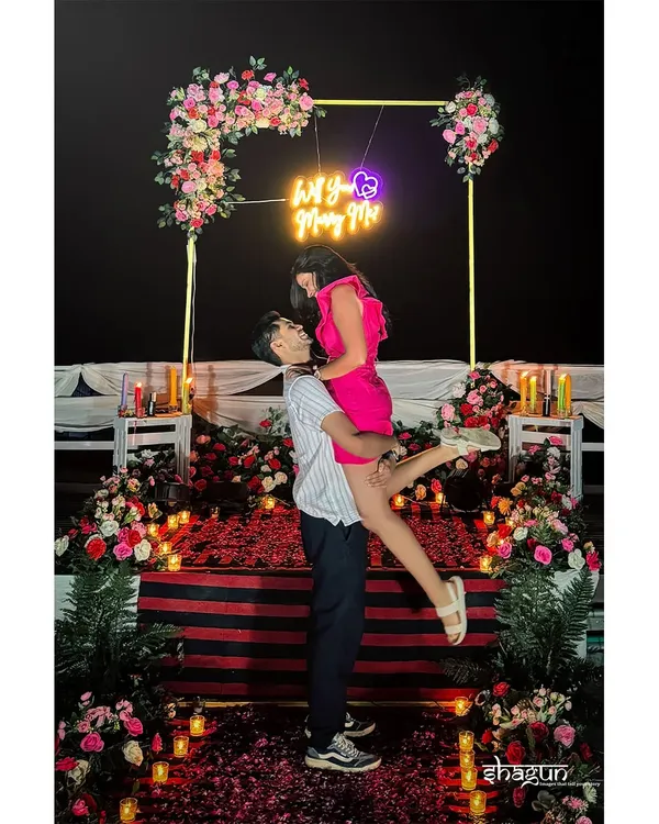 The moment she was swept off her feet! A "Will You Marry Me" neon sign, a bed of roses, and a joyful lift. This is how you create a proposal that is both grand and incredibly personal.