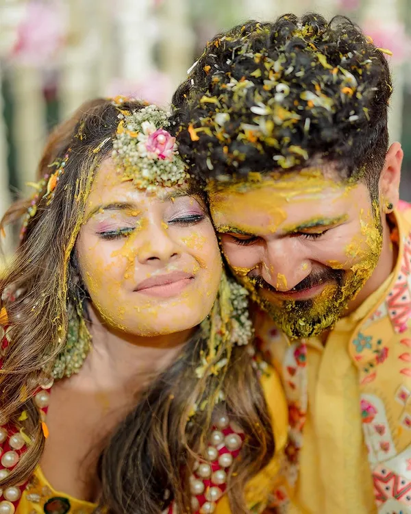 An intimate moment amidst the joyous chaos of the Haldi ceremony. The couple finds a quiet second together, covered in turmeric and love.