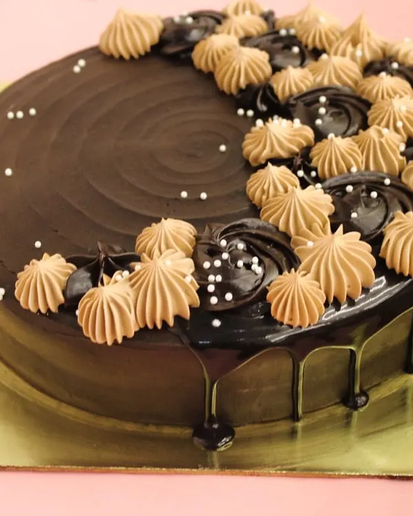 Our signature eggless chocolate cake is a top choice for celebrations. This design features a rich chocolate ganache drip and is elegantly topped with piped chocolate cream.