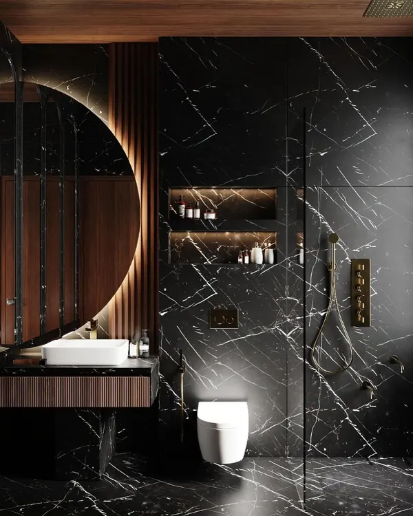 This bathroom is a study in dark, moody luxury. We used floor-to-ceiling black marble with dramatic white veining, a backlit circular mirror, and warm wood accents to create a sophisticated and intimate retreat.