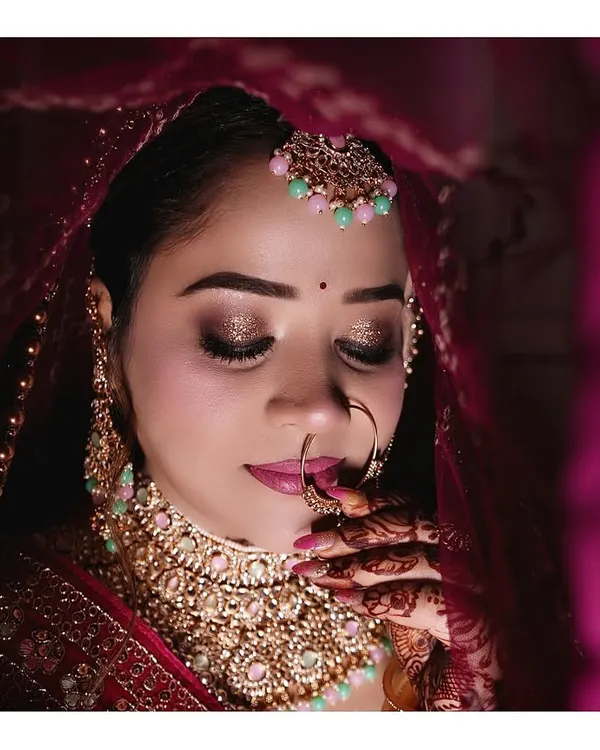 A stunning close-up bridal portrait with dramatic lighting. We focus on capturing the beauty of the bride's makeup, jewelry, and expression under a veil.