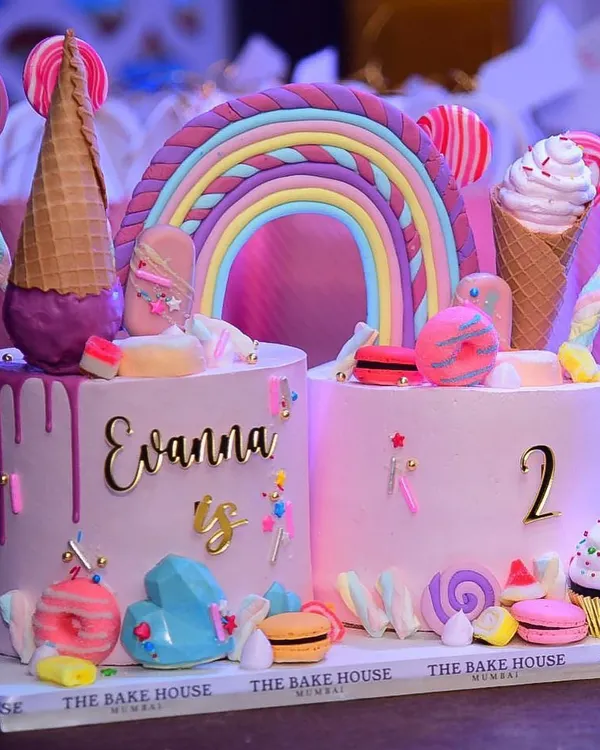 This "Too Sweet" themed double birthday cake was a joy to create for a second birthday party. It features two separate cakes connected by a fondant rainbow and decorated with macarons, lollipops, and ice cream cones for a truly magical look.