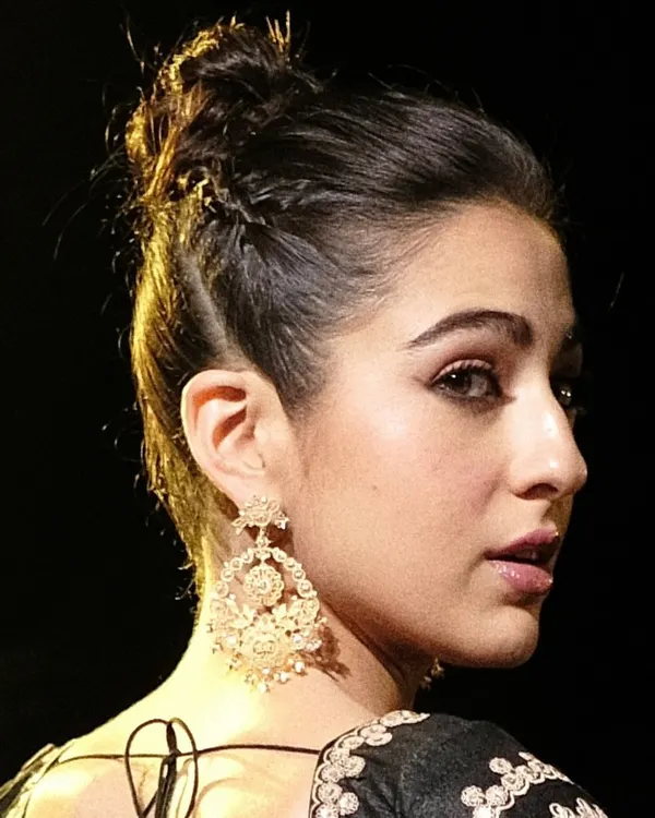 A close-up of the handcrafted 18k gold Chandbali earrings worn by Sara Ali Khan. This view highlights the intricate filigree work and the delicate pearls that dangle from the classic crescent moon shape.