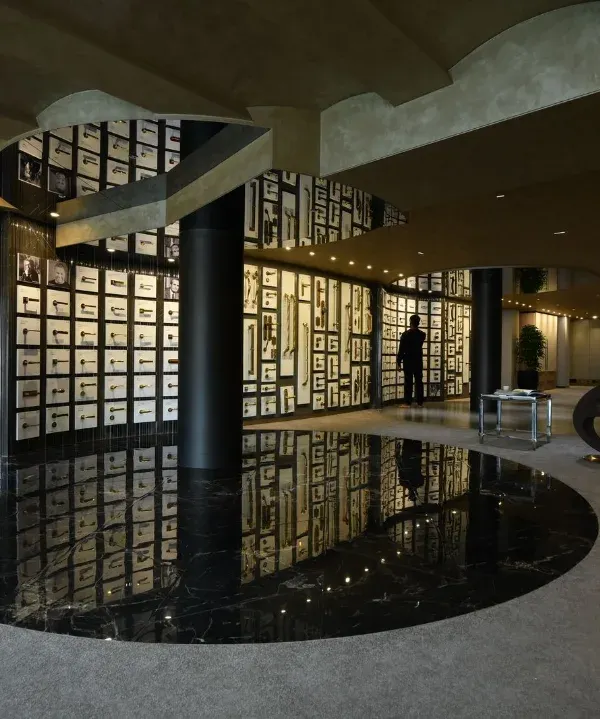 The Gala showroom, where a central black marble disc reflects the intricate display of architectural hardware on the walls. The design uses curves and dramatic lighting to create an immersive and high-end retail experience.