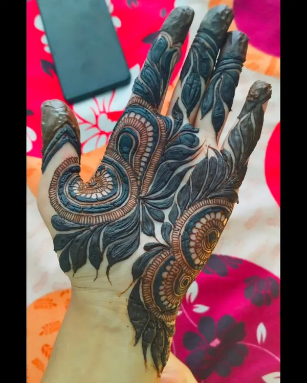 A finished Khaliji design with the henna paste applied. This style is known for its bold, dark-staining elements and the beautiful use of negative space on the skin.