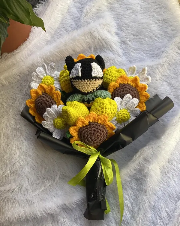 A full and vibrant Batman-themed bouquet. This custom order combines sunflowers, daisies, and yellow tulips with a Batman amigurumi nestled in the center.