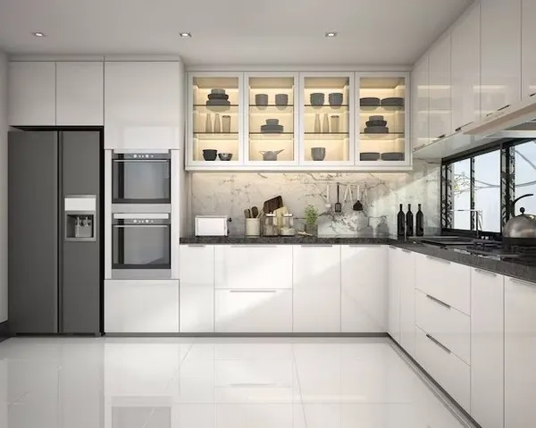 A pristine, all-white modular kitchen featuring handleless cabinets, built-in appliances, and illuminated glass-front upper cabinets for a sophisticated display.
