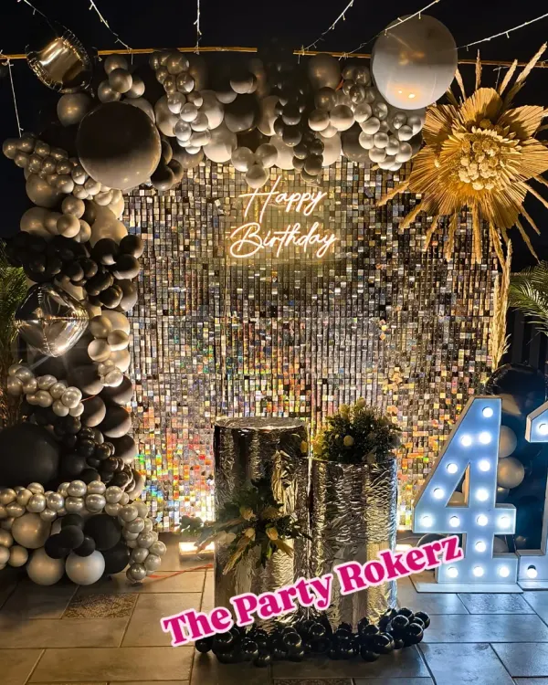 A stunning terrace setup for a 41st birthday party. We created this glamorous photo corner using a silver sequin wall, a custom neon sign, marquee numbers, and a black and silver organic balloon arch, perfect for nighttime celebrations.