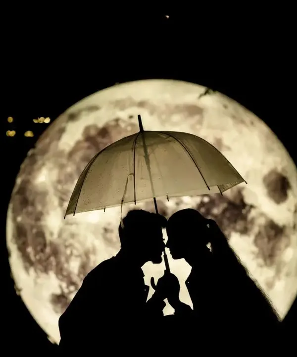 An iconic silhouette shot of a couple under an umbrella, perfectly framed by a giant, glowing moon. This is a highly creative and romantic concept that we love to execute.