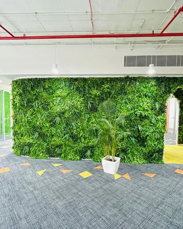 A large artificial vertical garden wall installed in a modern office space. It provides a huge splash of green with zero maintenance.