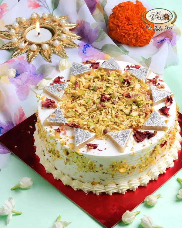 This is our showstopping Kaju Katli Cake. We've transformed the beloved cashew fudge into a rich, moist, pure vegetarian cake, generously topped with real kaju katli pieces, crunchy pistachios, and delicate rose petals for a truly festive treat.