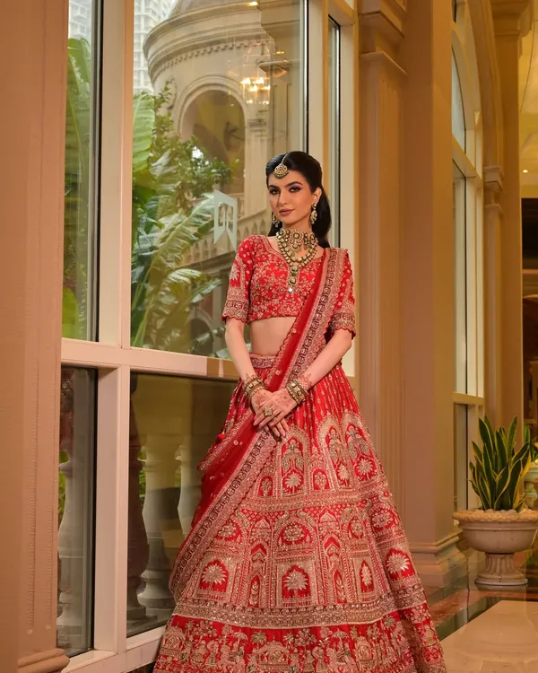 I believe in creating a look that is both regal and radiant. This classic red bridal lehenga, paired with exquisite Polki jewellery, showcases my signature 'Luxe Glam' style, ensuring you look and feel like modern royalty on your wedding day.