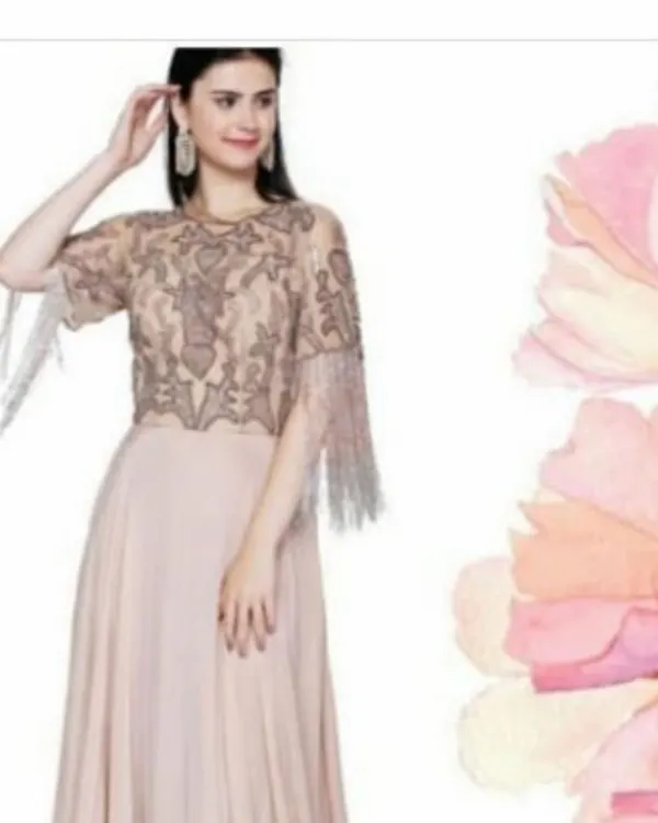 This beige gown features a stunningly detailed cape-style bodice with intricate beadwork and sparkling tassels on the sleeves. The flowing georgette skirt creates a graceful silhouette, perfect for any formal event.