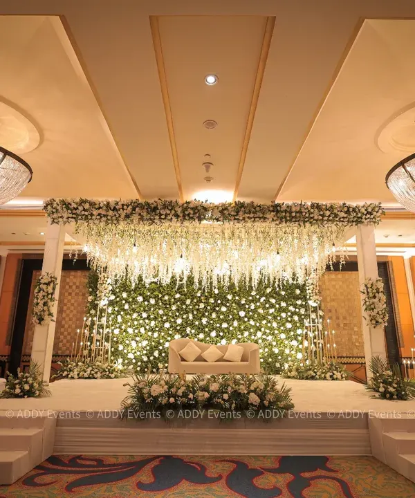This is the hero item. We specialize in creating breathtaking, elegant stages that serve as the perfect centerpiece for your grand celebration. This all-white floral stage, with a lush wall of blooms and cascading wisteria, was designed for a luxury wedding reception at the Radisson Blu MBD, creating a scene of pure grandeur.