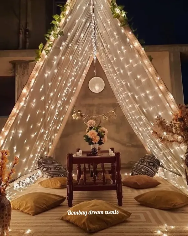 A romantic proposal and dinner date setup inside a beautifully lit tent on a rooftop. The fairy lights and cozy seating create a private, magical world for just the two of you.