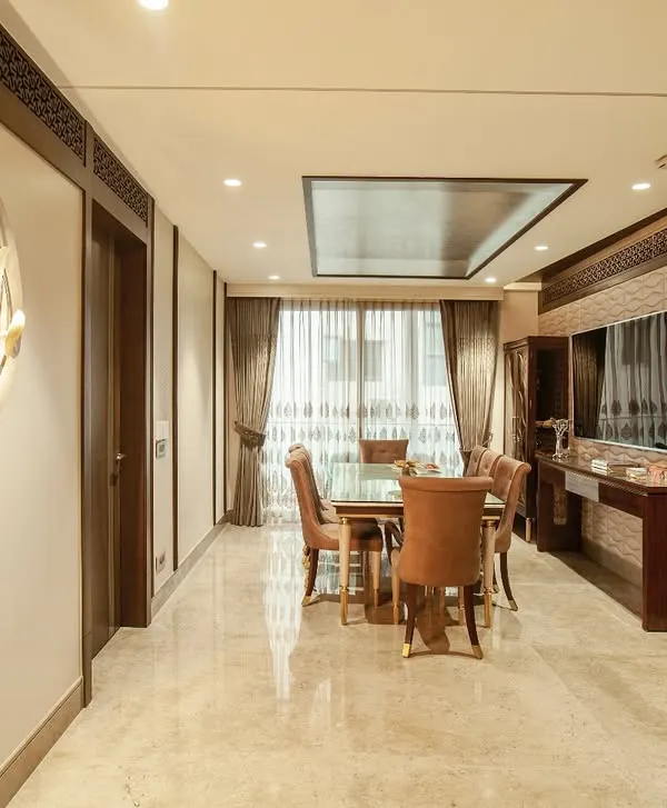 A classic dining setting where warm walnut furniture is set against beige walls and polished marble floors. The space is elevated by a sculptural gold wall mirror and custom display cabinets, creating an environment of quiet sophistication.