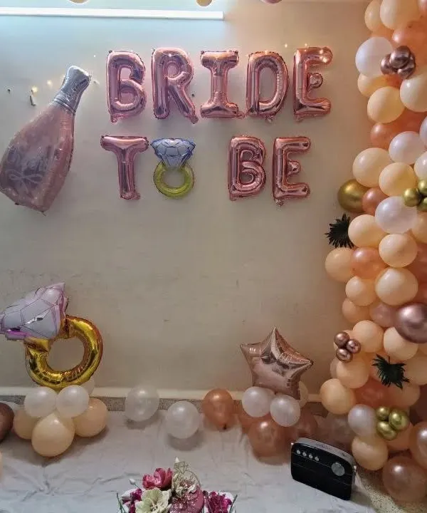 A complete 'Bride to be' decoration for a home party. This setup includes a rose gold and peach balloon garland with 'Bride To Be' foil balloons and other fun shapes.