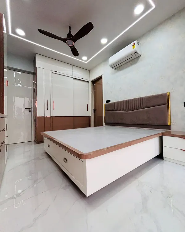 This master bedroom features a custom bed with a modern upholstered headboard and convenient bedside drawers. The false ceiling with cove lighting provides a soft, relaxing glow perfect for winding down.