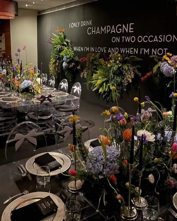 A breathtaking setup for an intimate sit-down dinner. The theme, "I only drink champagne on two occasions," sets a celebratory tone, with dramatic florals and elegant place settings.