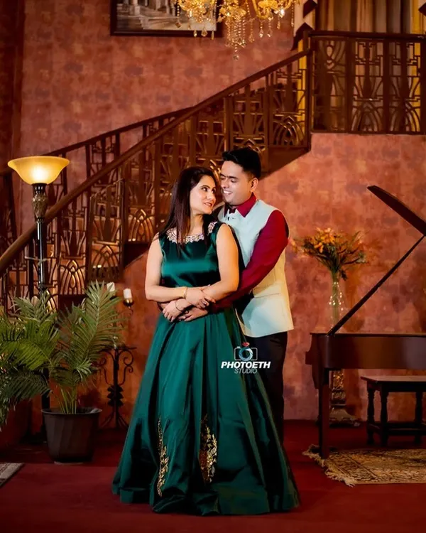A truly elegant pre-wedding portrait in a grand, wood-paneled room. The chandelier, grand piano, and the couple's formal attire create a look of timeless luxury.