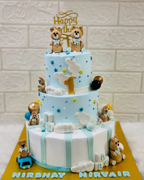 A grand three-tiered cake for a first birthday, decorated with adorable teddy bears, fluffy clouds, and stars. A perfect centerpiece for a memorable celebration.