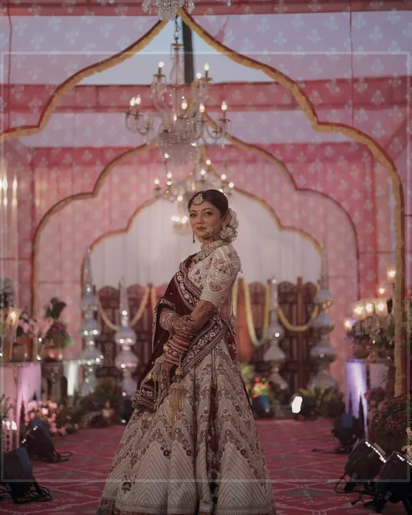A portrait of a radiant bride against the backdrop of her wedding decor. The intricate details of the mandap and her stunning lehenga come together to create a picture of pure elegance.