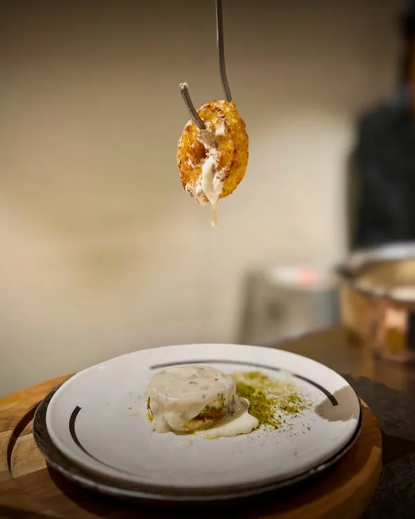 I love surprising guests with this savory Cheesy Donut. A golden fried ring filled with molten cheese is served dramatically off a hook, drizzled with a creamy sauce and finished with a fragrant basil crumble for a truly indulgent bite.