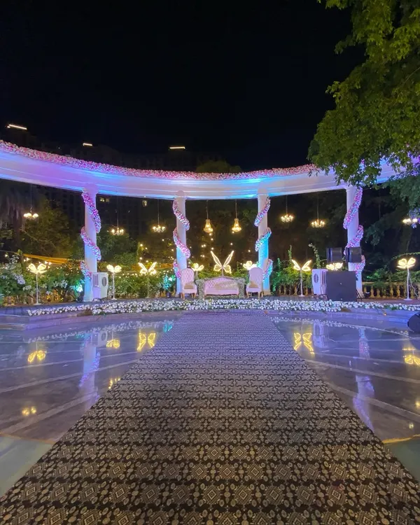 A wide view of the reception stage at Raheja Exotica, set against a serene poolside. The elegant white structure with butterfly accents and beautiful lighting created a magical focal point for the evening.