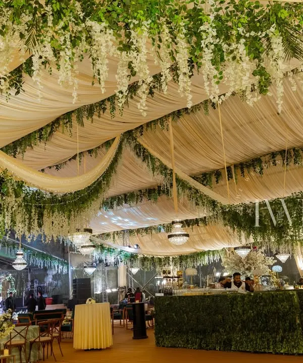 A 'Midsummer Night's Dream' Sangeet, where we created an enchanted garden inside a tent. The ceiling was draped with fabric and hanging wisteria, with a lush green bar running along the side.