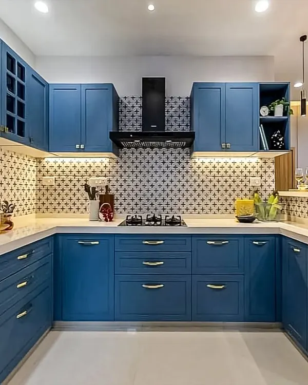 A beautiful U-shaped kitchen in a classic shaker style, painted in a calming shade of blue. The design is complemented by a patterned backsplash, white countertops, and elegant brass handles, creating a timeless and inviting space.