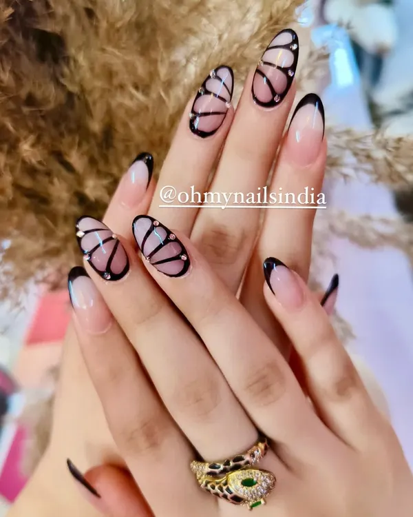 Believe in manicures that are a work of art. This intricate design features hand-painted butterfly wings with delicate black outlines and tiny crystal accents.