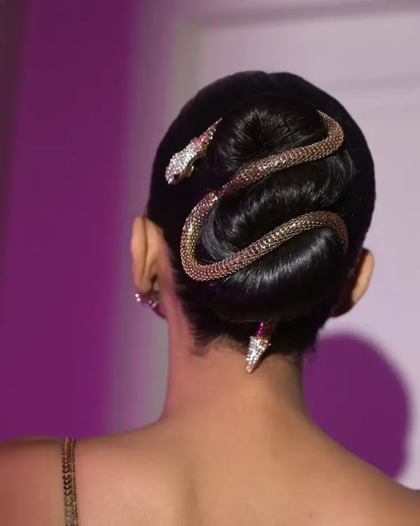 A close-up of the snake accessory coiled around the sleek bun. This shot highlights the precise placement and the high-impact detail that defines this editorial hairstyle.