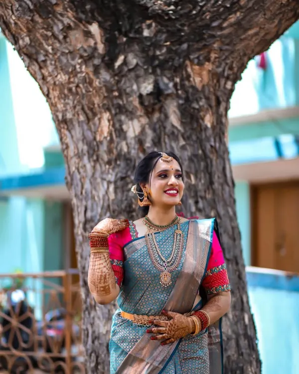 Our beautiful bride glowing in a teal blue silk saree with a contrasting pink embroidered blouse for one of her wedding functions.