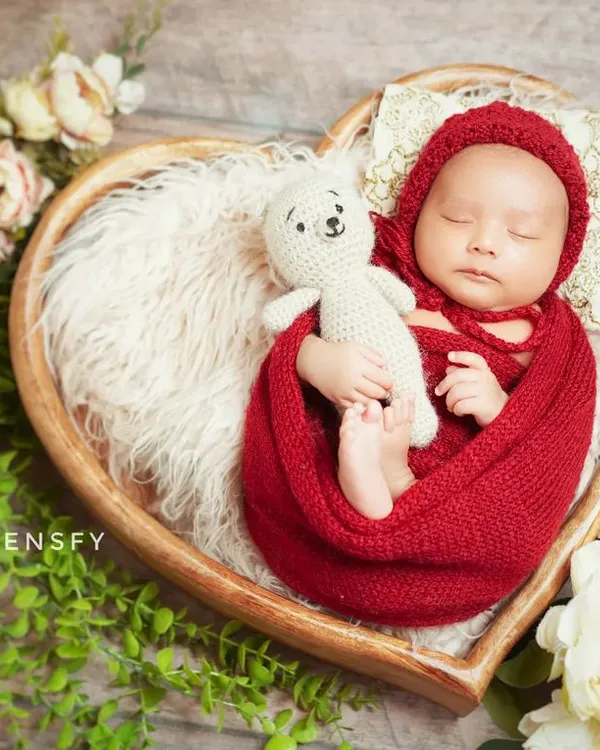 A perfect little newborn nestled in a heart-shaped basket. I use cozy wraps and props like this to ensure your baby is safe, comfortable, and looks absolutely adorable.