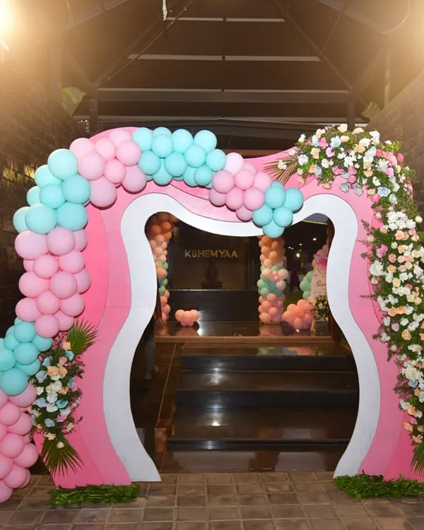 This custom-designed entrance arch for a butterfly-themed party is truly one of a kind. The unique shape is decorated with pink and mint balloons and fresh flowers for a grand and memorable welcome.