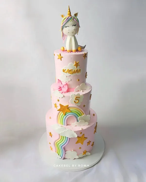 A three-tier unicorn cake that is pure magic. Dressed in soft pink, this cake features cascading rainbows, golden stars, and an adorable fondant unicorn on top, making it a dreamy centerpiece for a 5th birthday.