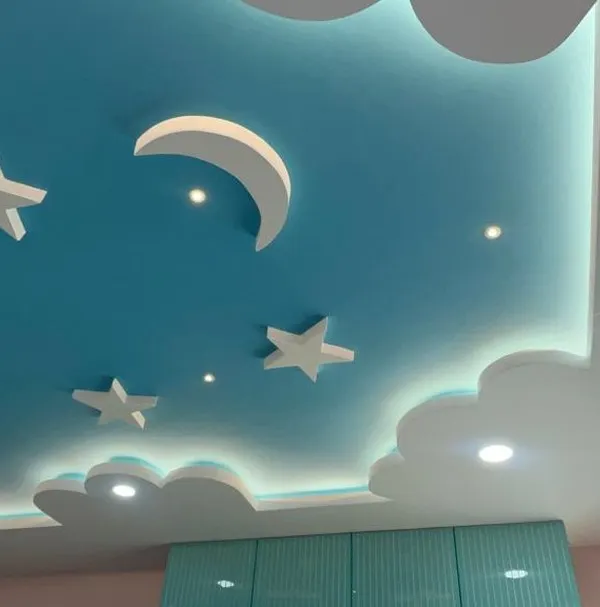 A dreamy false ceiling design for a kids' room, featuring a blue sky with clouds, a moon, and stars. The backlit clouds create a soft, magical glow, perfect for bedtime stories.
