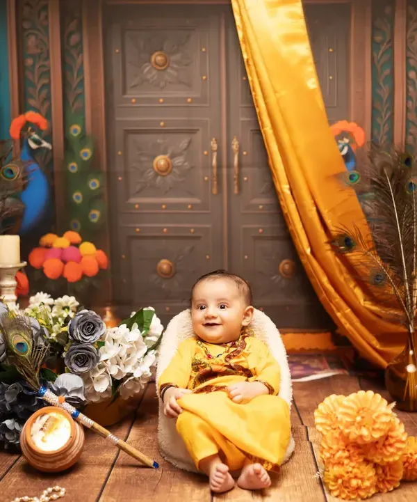 A grand and colorful setup for a baby's Janmashtami photoshoot. This Krishna-themed set features traditional elements like peacock feathers, pots, and rich fabrics.