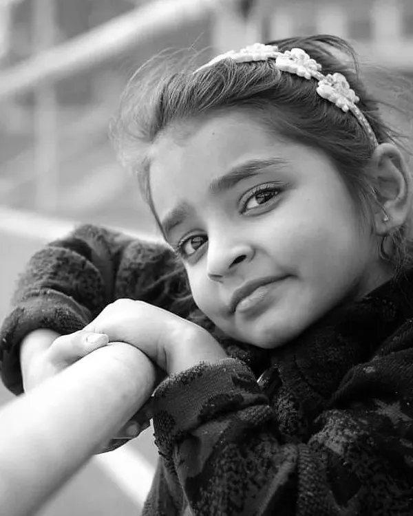 A classic black and white portrait of a young girl. The monochrome style emphasizes her gentle expression and captures a timeless, candid moment.