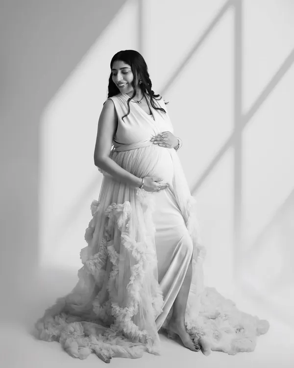 A beautiful black and white portrait of a mom-to-be in a ruffled gown. The window light effect adds depth and artistry to this timeless image.