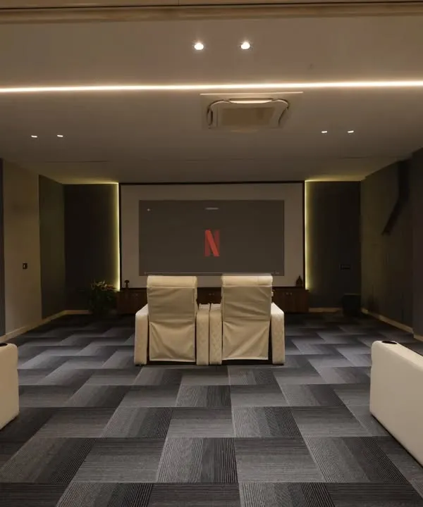 This home theater is designed for an immersive movie experience, with a large screen, acoustic wall panels, and comfortable recliner chairs.
