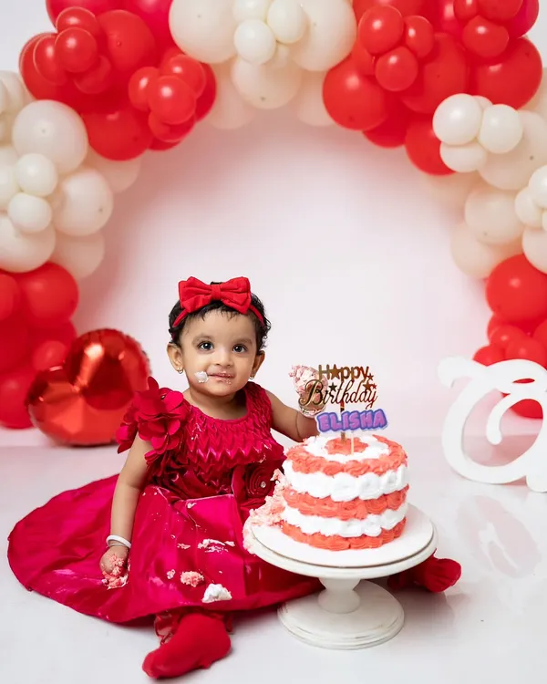 A perfect first birthday portrait with a red and white theme. She's just getting a little taste of the cake before the real smashing begins.