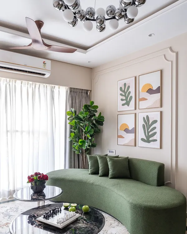 A modern living room from 'Project Modern Muse' featuring a stylish curved green sofa, abstract wall art, and a striking globe chandelier.