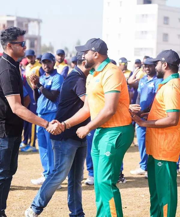 A moment of sportsmanship captured at the Indian Corporate Cricket League, with players shaking hands.