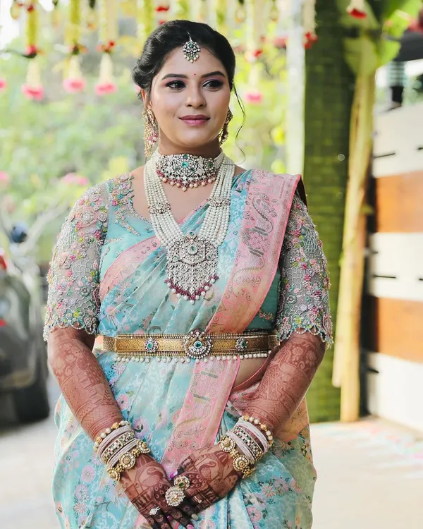 The personification of elegance and beauty. This gorgeous bride is wearing a full bridal mehendi that complements her stunning pastel blue and pink saree and pearl jewelry.