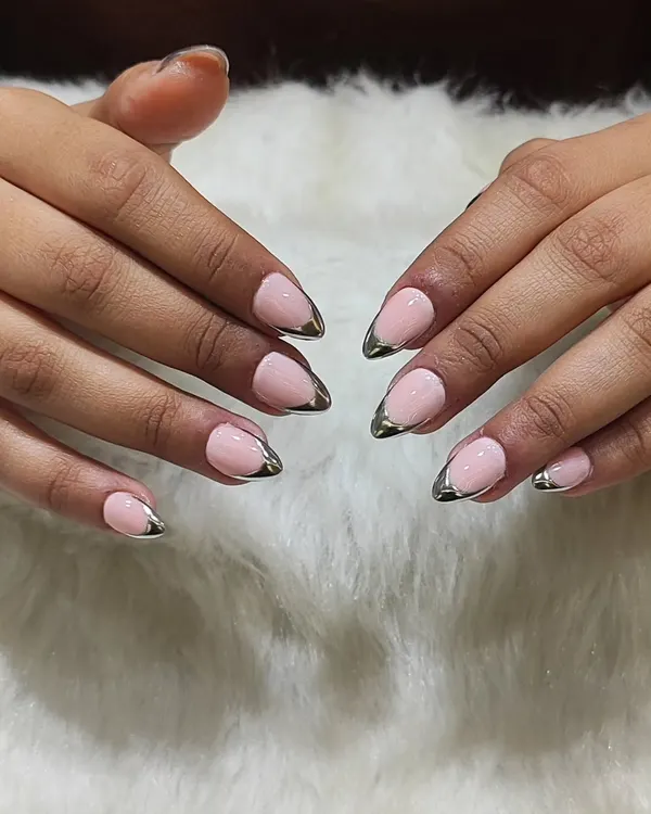 A chic and modern take on a classic. This look features a soft pink base with a metallic silver chrome tip, updating the traditional French manicure with an edgy, futuristic feel.