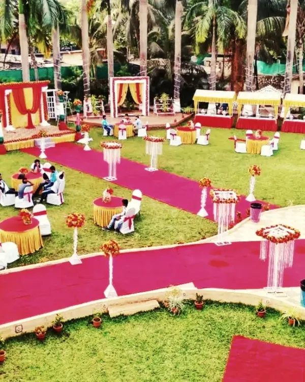 An aerial view of a large outdoor wedding setup on a lawn, showing the stage, guest seating, and red carpet walkways all arranged by my team.