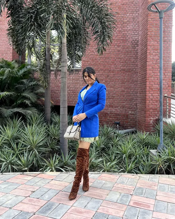 A full-length view of this bold street style look. I paired a royal blue blazer with a short, light green printed dress and finished it with daring leopard-print thigh-high boots and a designer bag. This is how you make a statement on a regular day.
