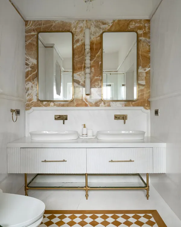 The master en-suite at Verdant Manor, anchored by a dramatic Mango Onyx accent wall and a floating white vanity. We used fluted detailing on the drawers and a checkerboard floor tile pattern to add layers of texture and geometry.