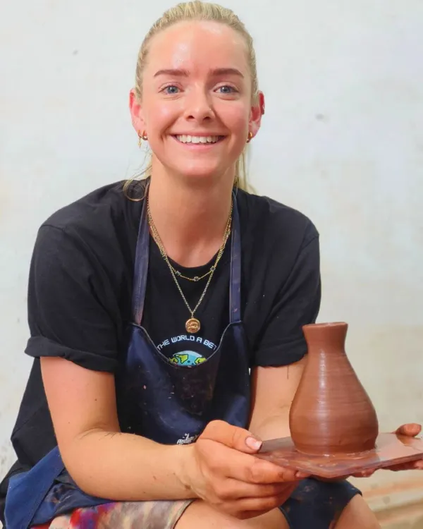 A smiling traveler from abroad proudly holds up the vase she made in our workshop. We are honored to welcome visitors from around the world to experience Indian art and culture firsthand.